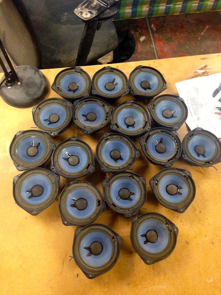 Drivers with bad surrounds sitting all in a pile on a workbench.